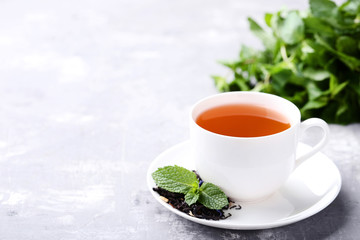 Cup of tea with mint leafs on grey wooden table