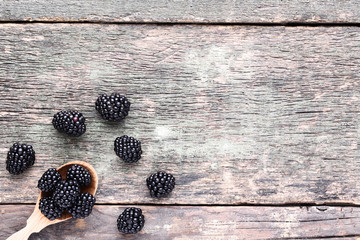 Ripe blackberries with spoon on grey wooden table
