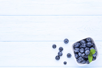 Ripe blueberries with green leafs on wooden table