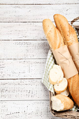 Fresh baguettes with napkin in basket on wooden table