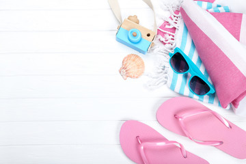 Pair of flip flops with sunglasses, towels and seashell on white background
