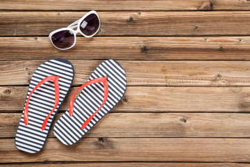 Pair of flip flops with sunglasses on brown wooden table