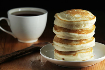 A stack of freshly backed pancakes and a cup of coffee