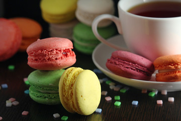 Bright macaroons with a cup of coffee against dark background