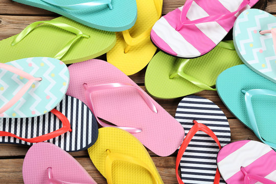 Pairs of colorful flip flops on brown wooden table