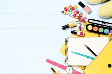 Makeup cosmetics with bag and notepad on wooden table