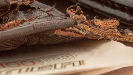 macro photo of old torn brown wallet with money bills