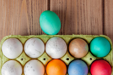 Colorful Easter eggs in box on wooden background with copy space