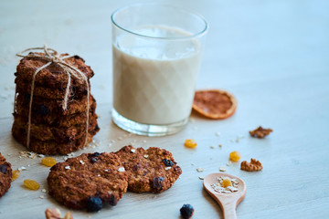 Homemade oatmeal cookies with walnut, raisins and milk on a wooden table