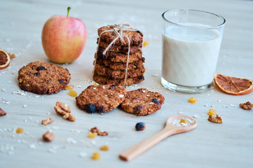 Homemade oatmeal cookies with walnut, raisins and milk on a wooden table