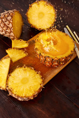Splash fresh fruit juice with exotic pineapple on a wooden brown table. A composition made of ananas. Top wiev. 