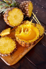 Splash fresh fruit juice with exotic pineapple on a wooden brown table. A composition made of ananas. Top wiev. 