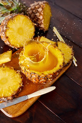 Splash fresh fruit juice with exotic pineapple on a wooden brown table. A composition made of ananas. Top wiev. 