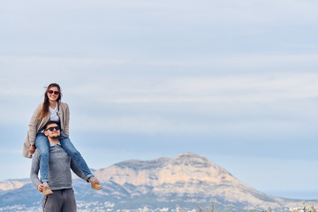 Young cute girl sitting on shoulders of her boyfriend