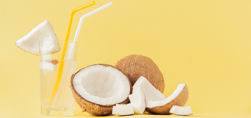 Fresh Coconut cocktail with a straws on yellow background