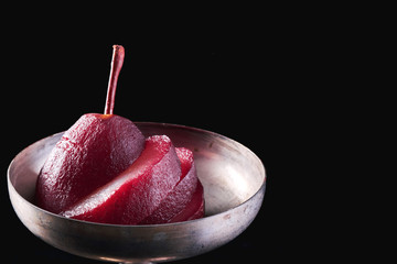 Close-up of a pear in red wine isolated on black background