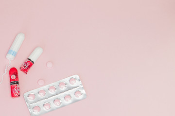 Sanitary pads and tampons and pills on pink background. Woman critical days, gynecological menstruation cycle. Menstruation sanitary woman hygiene. Medical concept.Top view, flat lay, copy space