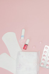 Sanitary pads and tampons and pills on pink background. Woman critical days, gynecological menstruation cycle. Menstruation sanitary woman hygiene. Medical concept.Top view, flat lay, copy space