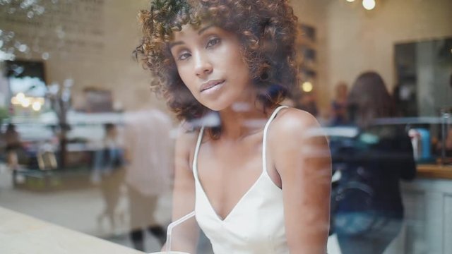 Beautiful american woman in a cafe, view through the glass window