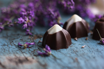 Heart chocolate candies, gift box, lavender flowers bunch and love symbols on planks. Romantic vintage background