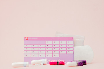 Tampon, feminine, sanitary pads for critical days, feminine calendar, pain pills during menstruation on a pink background. Tracking the menstrual cycle and ovulation