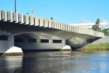 Calm waters of Yarra River in Melbourne flowing under white Swan Street Bridge.