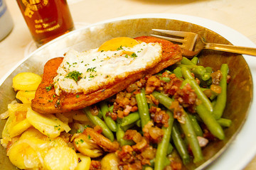 fried eggs with potatoes bacon and vegetables on a plate