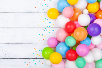 Colorful balloons and confetti on white table top view. Festive or party background. Flat lay....