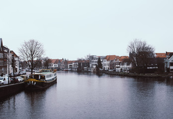 Calm view of Spaarne river in Haarlem, Netherlands. Dark shadows cast on the waves. Water reflecting buildings of a small town.