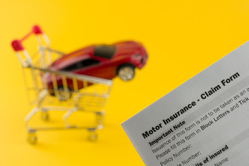 red car in a shopping cart insurance document. short term car insurance concept. yellow background