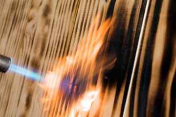 torch flame burns wood, close up wooden background