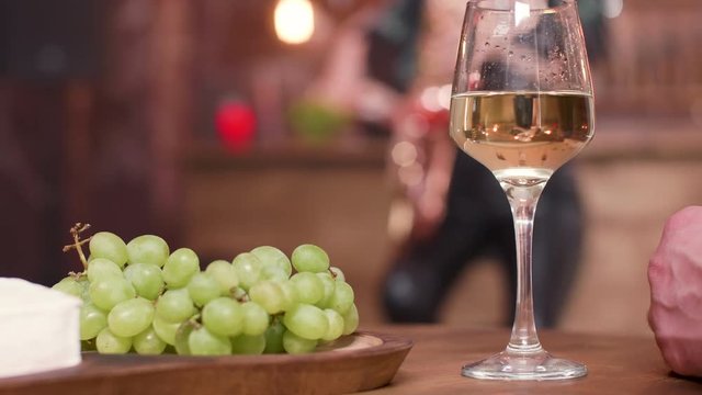 A glass of white wine and grapes on a wooden table. Appetizers on a restaurant table.