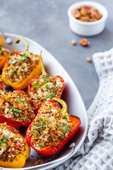 Vegetarian dish with peppers stuffed with quinoa, onion and tomato, sprinkled with walnuts.