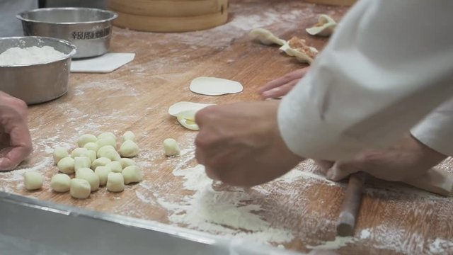 Closeup of making process of Chinese dumpling inside the kitchen. Hand preparations including pastry massage and mince pork, prawn, vegetable wrap. Wide ratio of 16:9.
