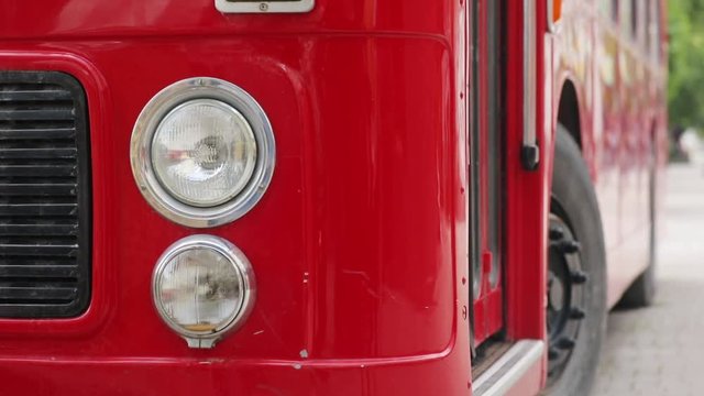 Close-up front view of the headlights of the red double decker bus on the street in modern city.