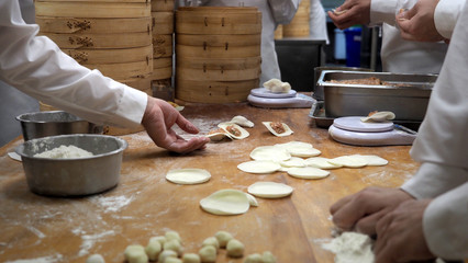 Closeup of making process of Chinese dumpling inside the kitchen. Hand preparations including pastry massage and mince pork, prawn, vegetable wrap.