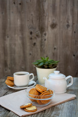 Ginger cookies with cream, biscuit for tea of coffee, on wooden table. Sweet healthy food snack with coffee, tea cup.