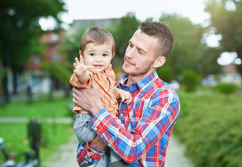 father holds son in a park