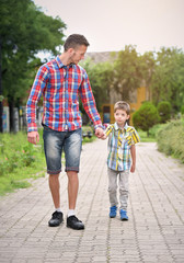 father holding hand with son in a park