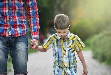 father holding hand with son in a park