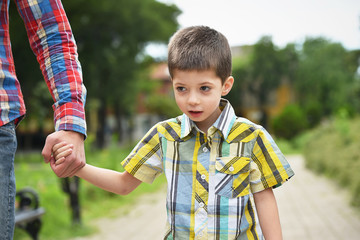 father holding hand with son in a park