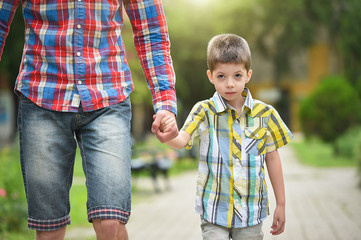father holding hand with son in a park