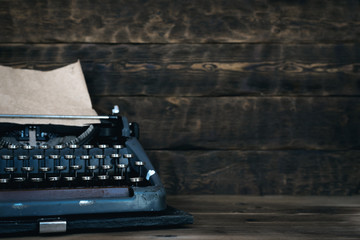 Old typewriter on a writer wooden desk background with copy space.