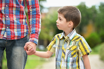 father holding hand with son in a park