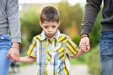 mother, father and son holding hands in park