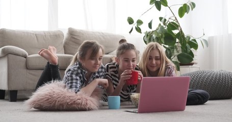Teenage roommates drinking coffee and eating popcorn - Powered by Adobe