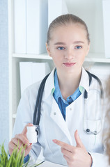 Beautiful smiling female doctor hold in arms pill bottle and offer it to visitor. Antidepressant or vitamins for healthy life.