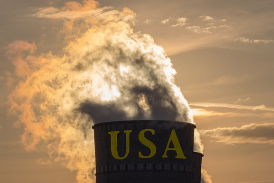 Industrial exhaust pipe with inscription USA against the sky and smoke at sunset