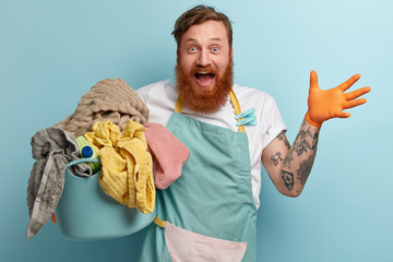 Overjoyed red haired man with foxy thick beard, raises hand, being very happy, wears casual t shirt...