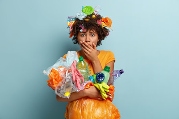 Oh no, use less plastic. Emotional surprised fearful female covers mouth, collects plastic trash,...